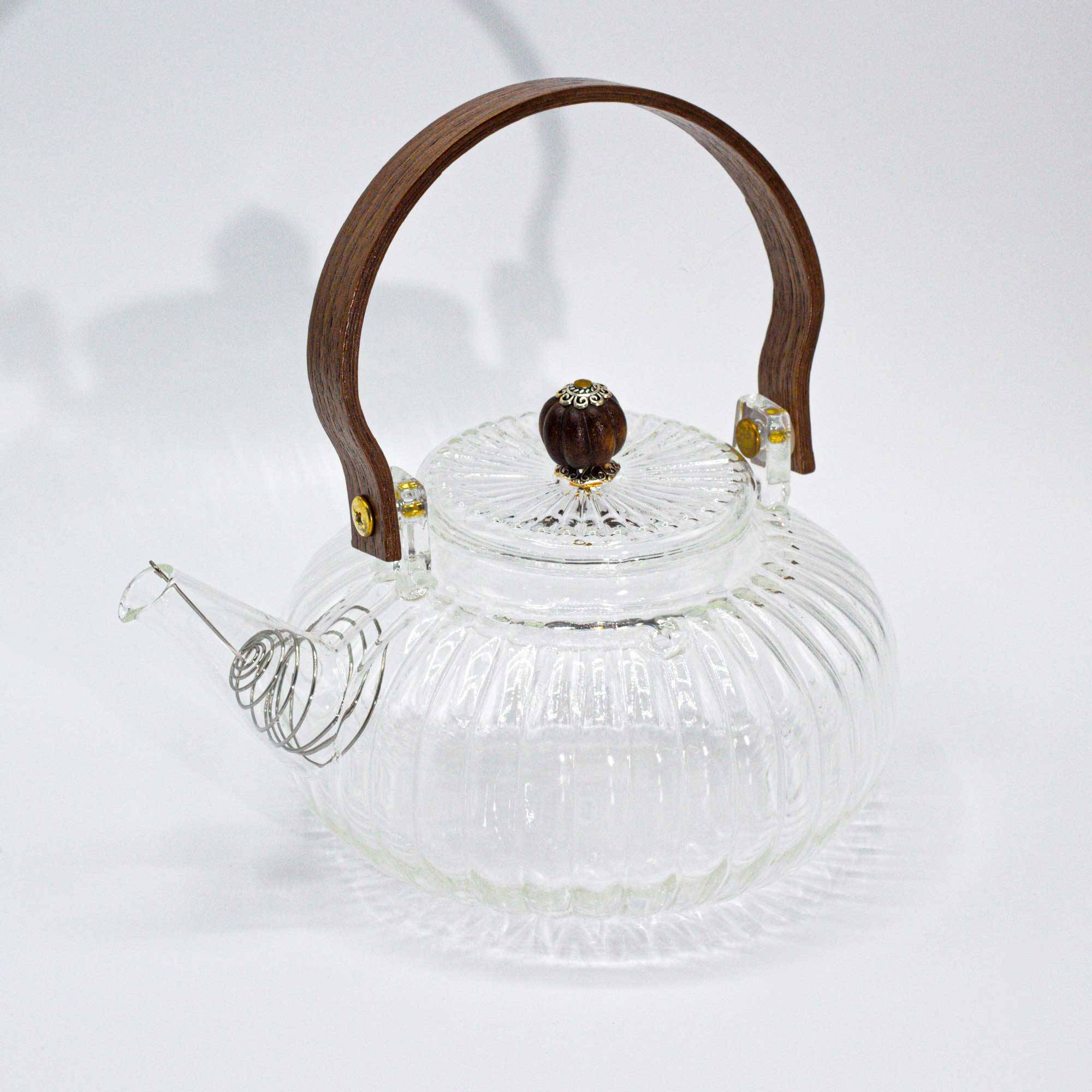 Clear glass teapot with a ribbed design, wooden handle, and wooden knob on the lid, displayed on a white background.
