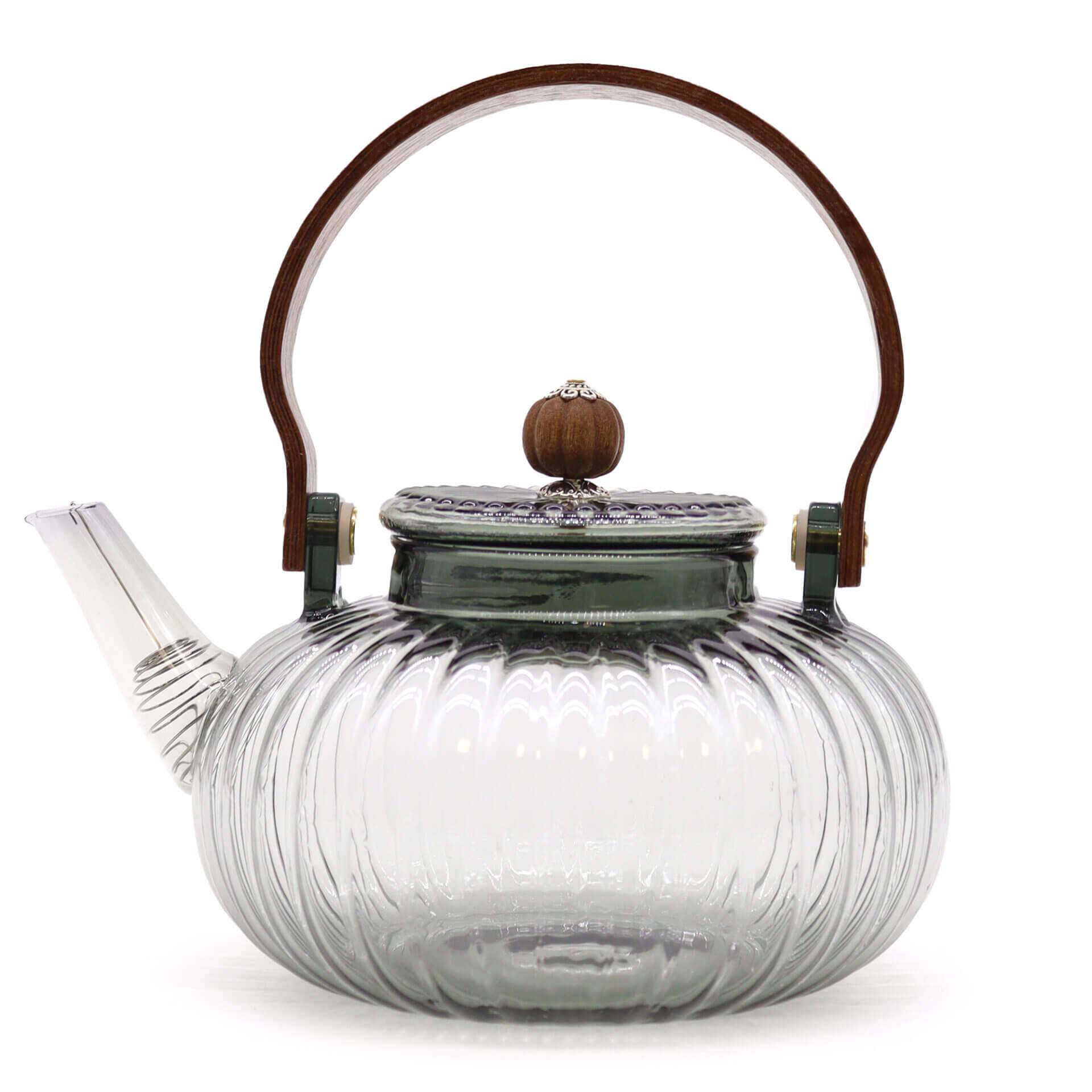 Clear glass teapot with a ribbed design, short spout, metal lid topped with a wood knob, and a curved wooden handle.