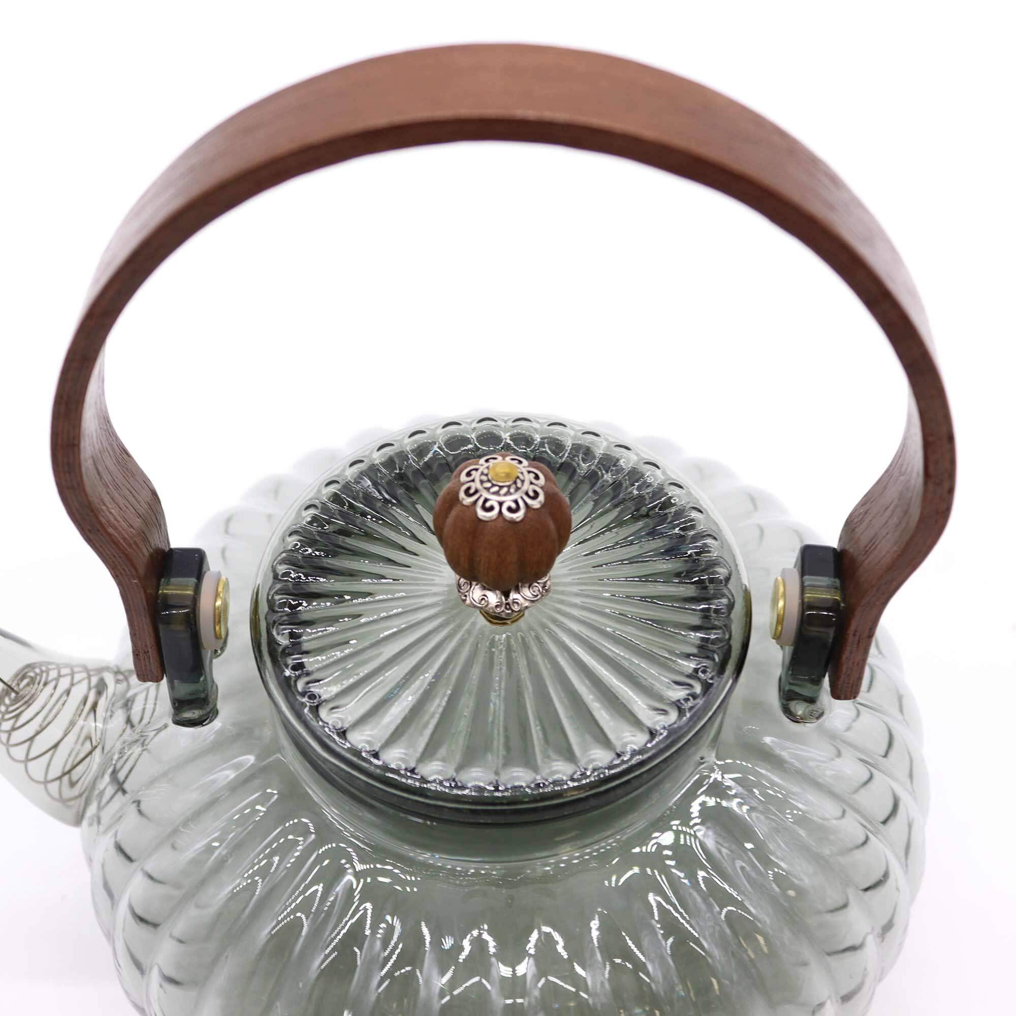 Clear glass teapot with a ribbed design, wooden handle, and a matching ribbed glass lid featuring a decorative wooden knob with a small floral detail.