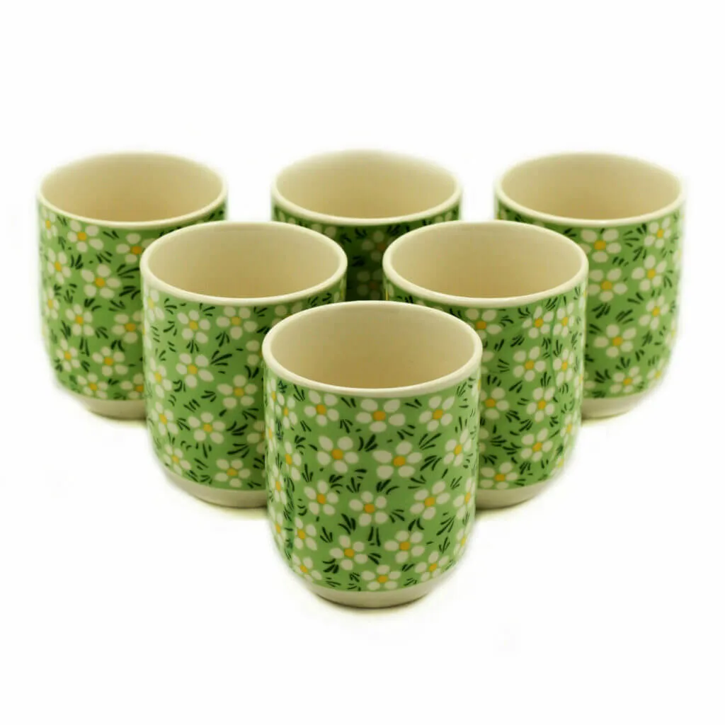 Six ceramic cups with a green background and white floral pattern, arranged in two rows on a white surface.
