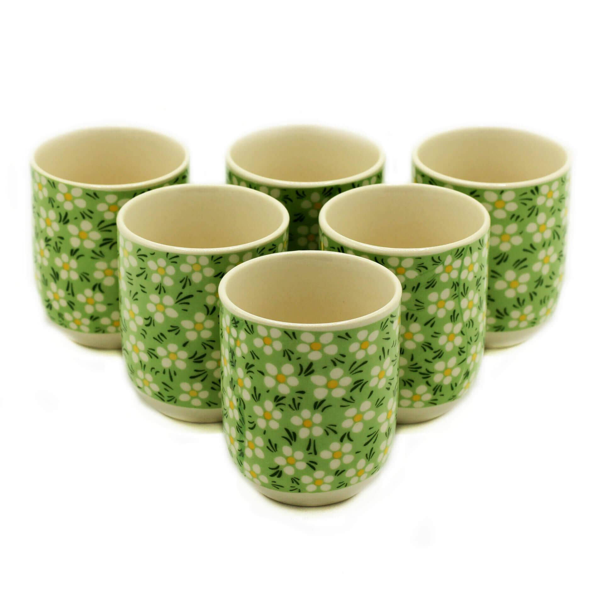 Six ceramic cups with a green background and white floral pattern, arranged in two rows on a white surface.