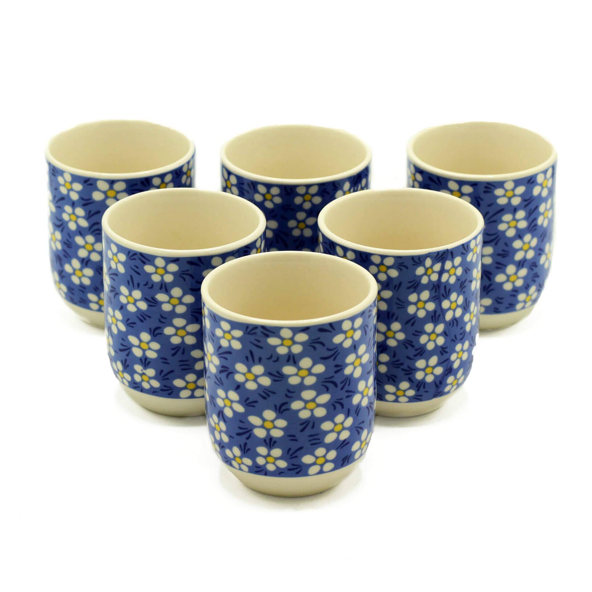 Six ceramic cups with a blue background and white floral pattern arranged in two rows on a white surface.