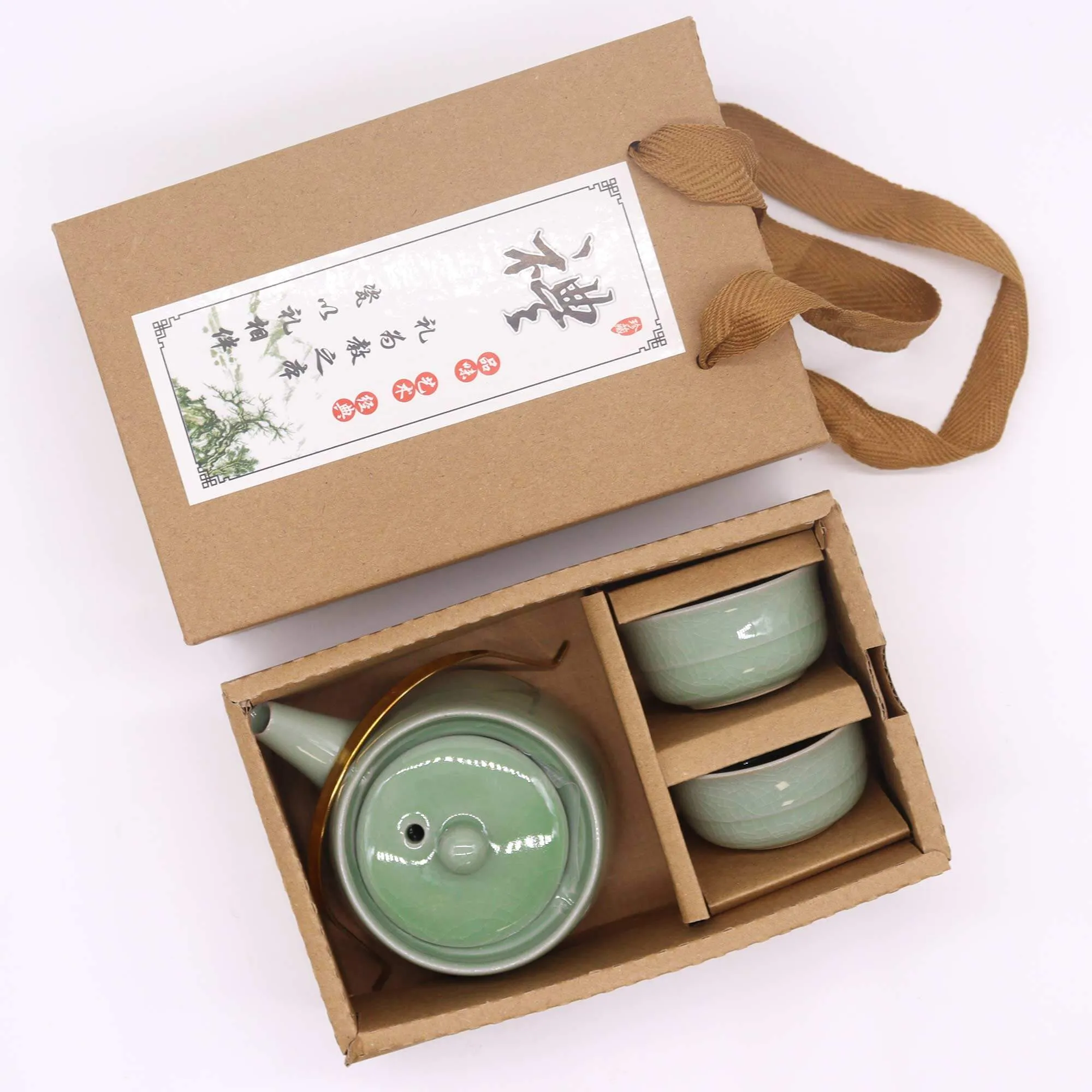 A boxed set containing a green ceramic teapot and two matching cups with a brown handle attached to the packaging.