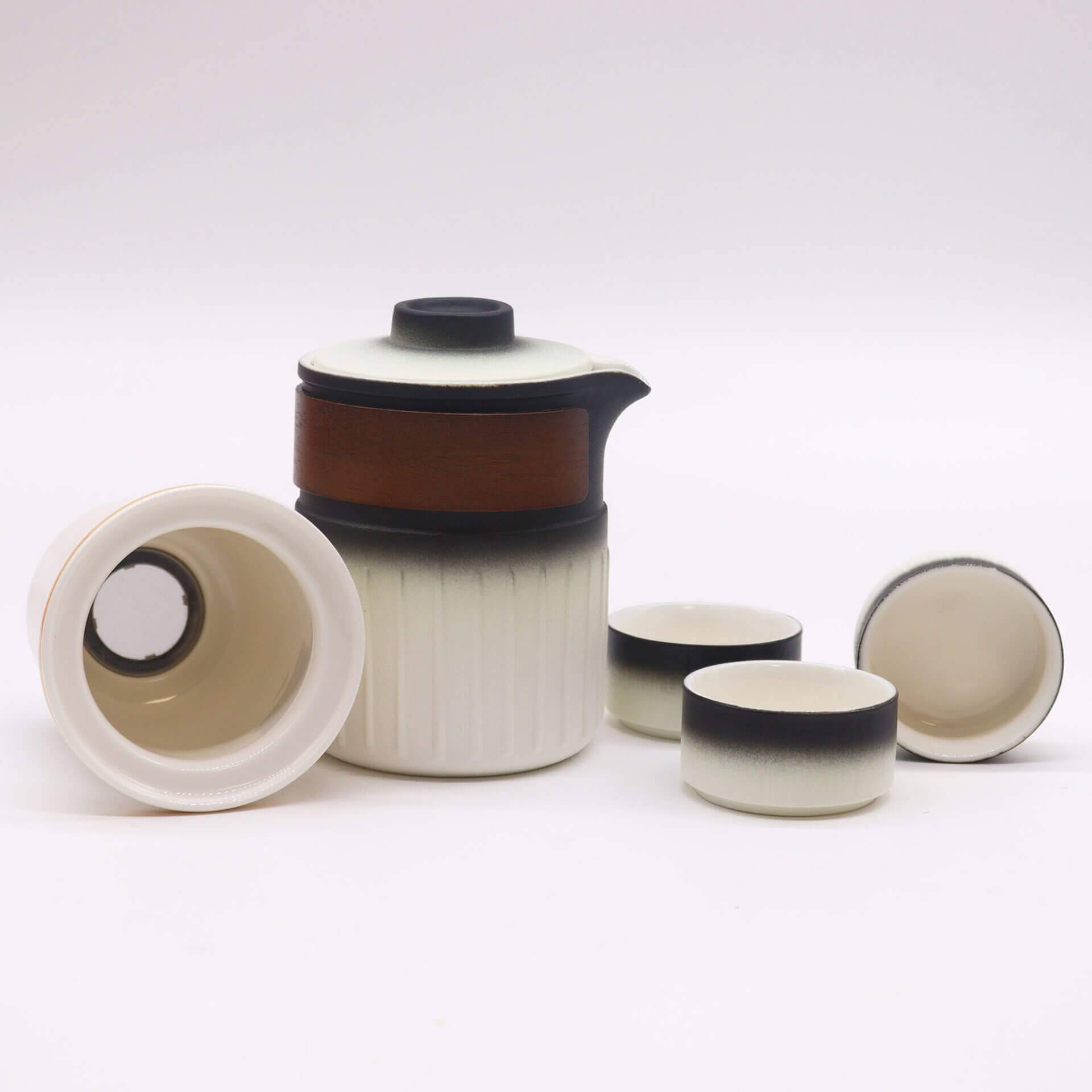 A ceramic tea set with a lidded teapot and three cups, all in a white and black gradient design, displayed on a plain white background.