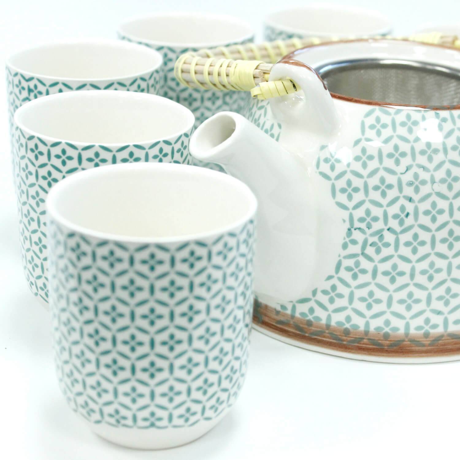 A patterned ceramic teapot with a handle and five matching cups arranged around it, all on a white background.