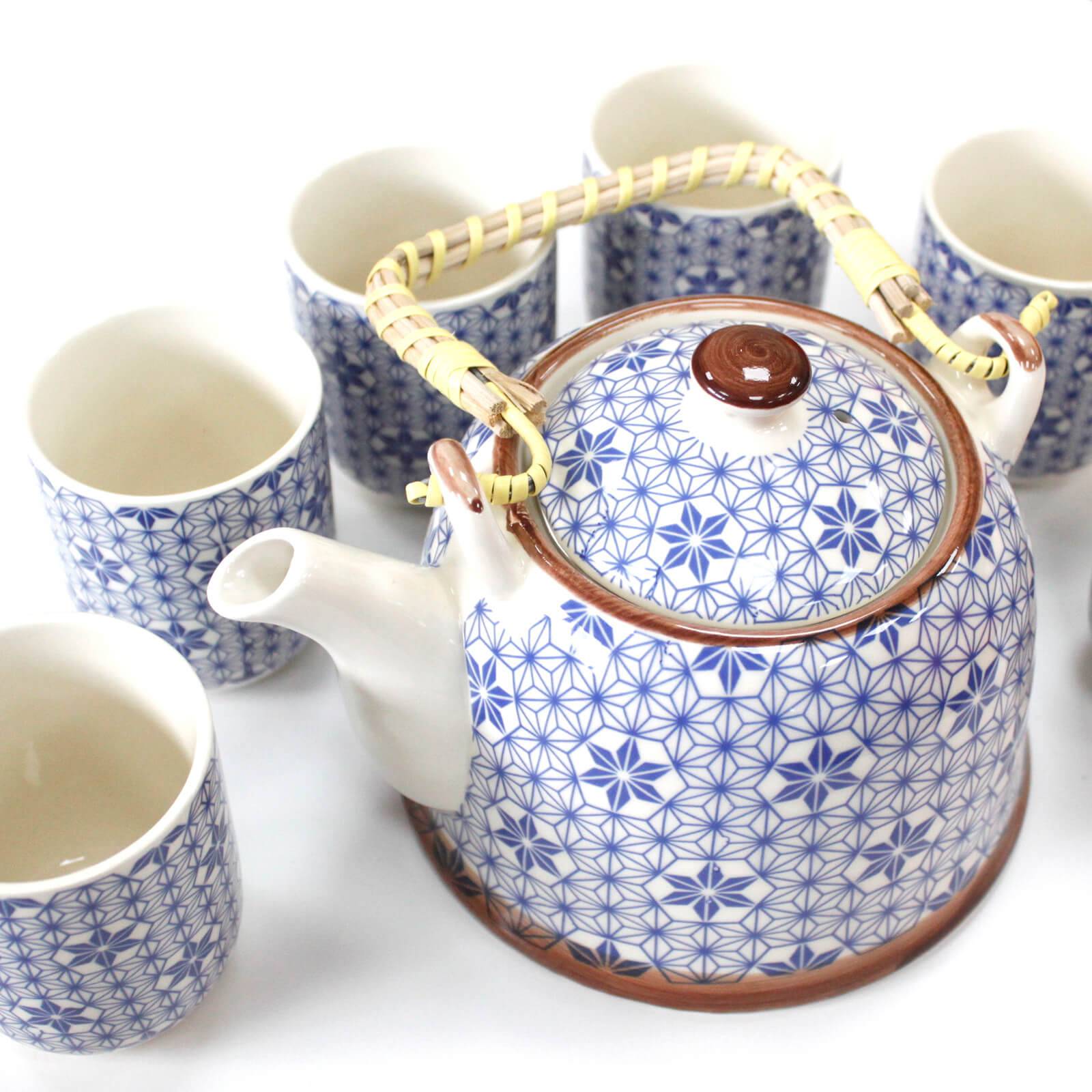 A ceramic teapot with a woven handle and blue geometric pattern is surrounded by six matching cups, all on a white background.