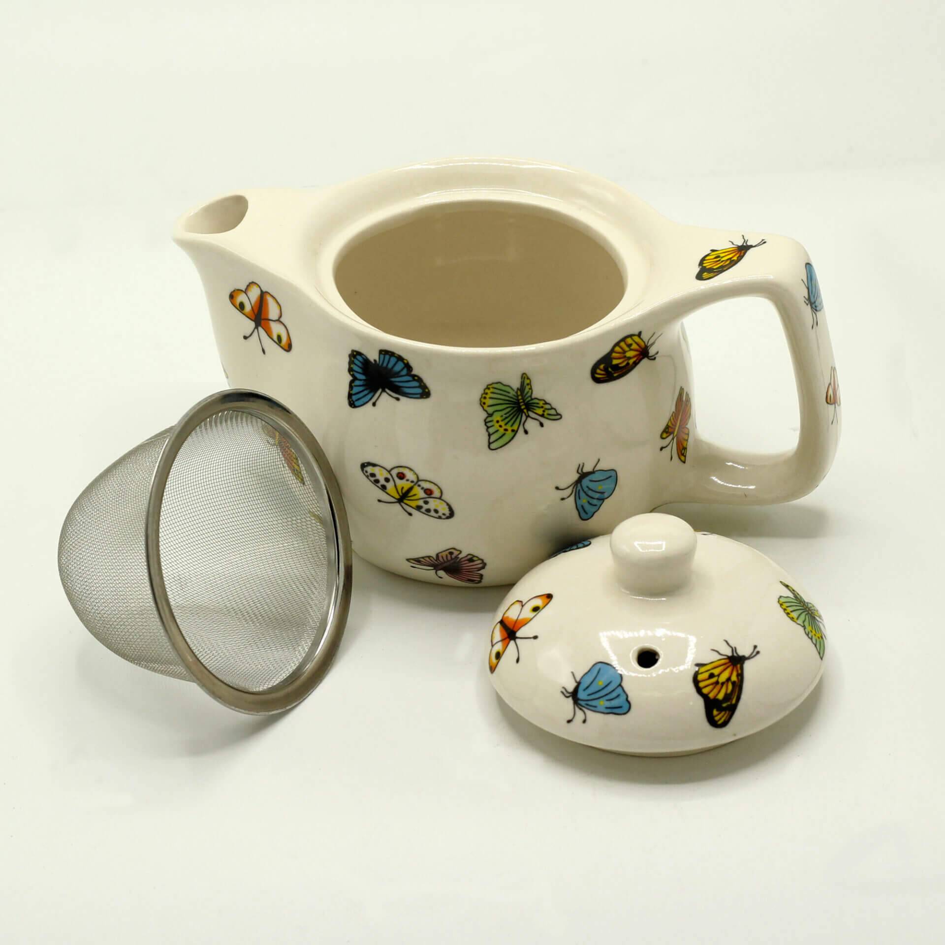 White ceramic teapot with colorful butterfly designs, shown with its lid removed and a metal mesh infuser placed beside it.