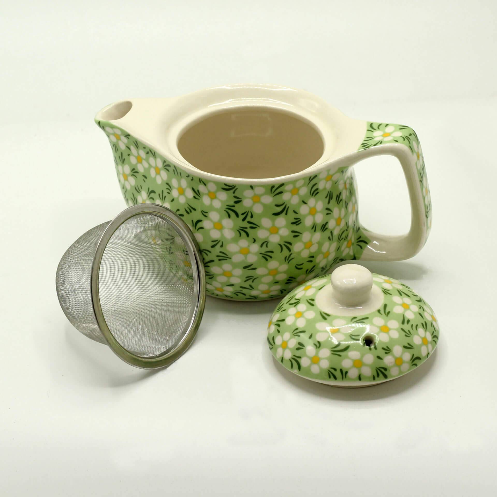 A ceramic teapot with a green and white floral pattern, shown with its lid and a metal tea infuser placed beside it.