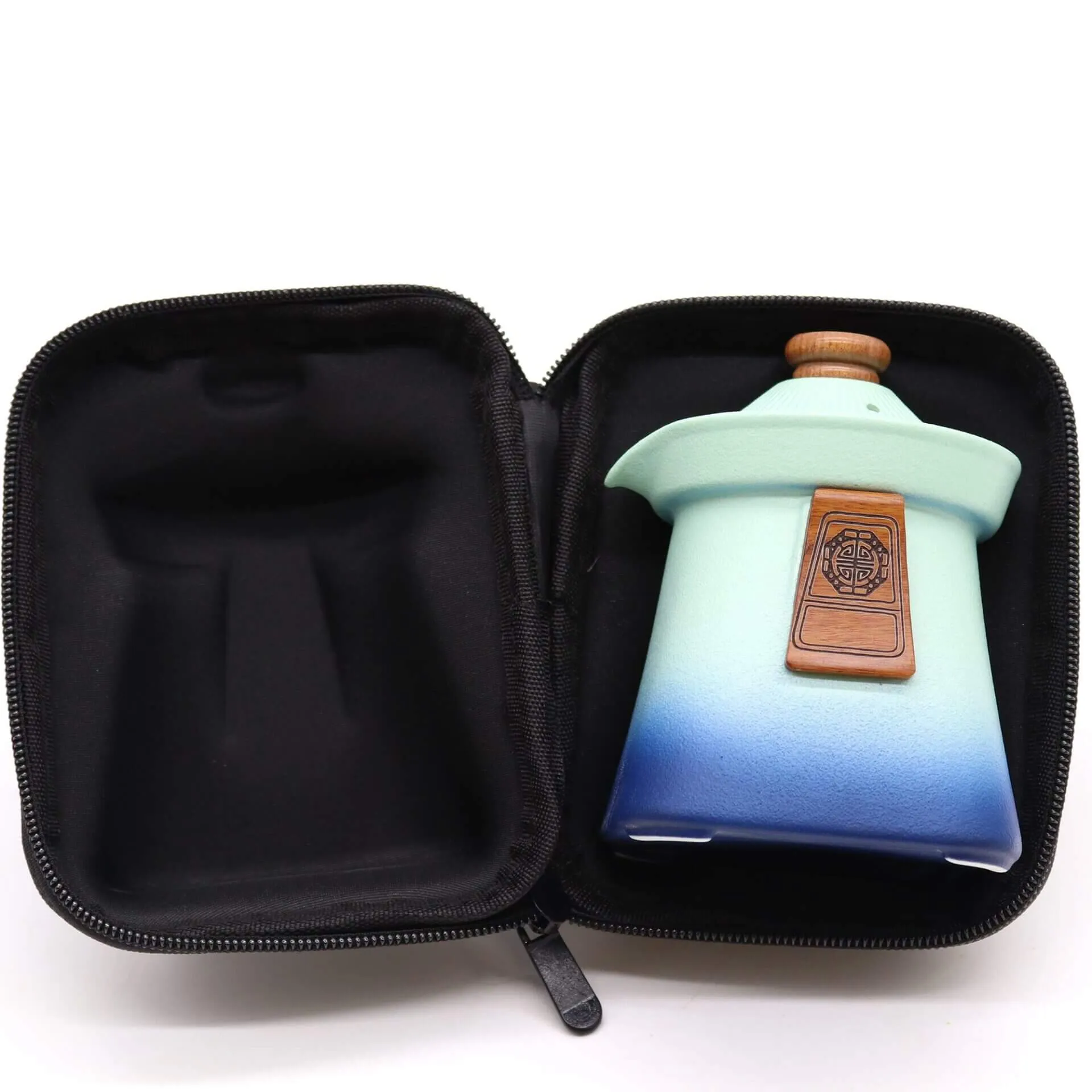 A small, gradient blue and green ceramic jar with a wooden lid and emblem is placed inside an open black zippered carrying case.