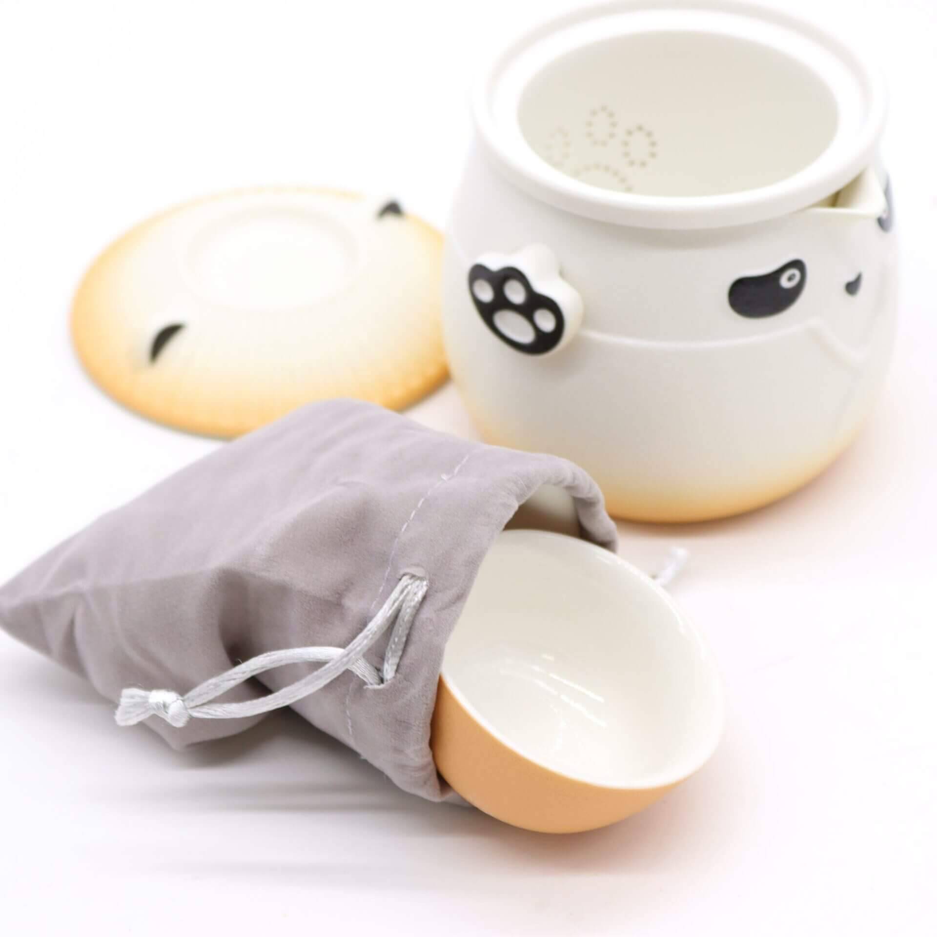 A ceramic jar with animal paw prints, a matching lid, and a small bowl partially inside a gray drawstring pouch are shown on a white background.