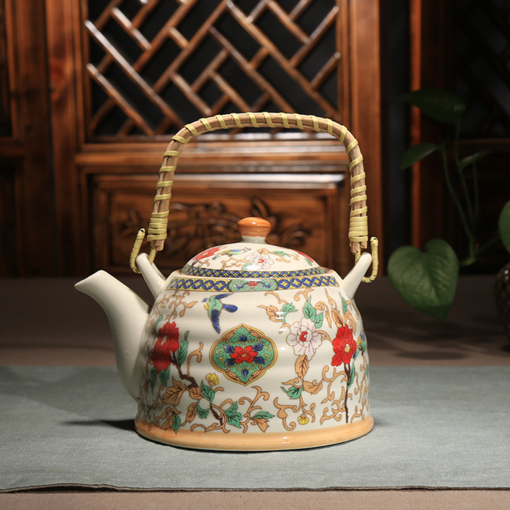 A ceramic teapot with a decorative floral pattern and a woven handle sits on a table with a wooden lattice background.