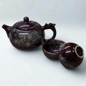 The Ocean Blue Teapot for One is an aqua teal tea set with 2 cups, featuring a glossy marbled finish and round lid, inspired by ocean hues, and elegantly displayed on a plain white background.