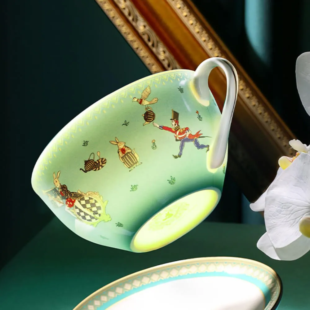 A green teacup with whimsical illustrations, including a rabbit and checkered pattern, is suspended in mid-air near a white orchid.