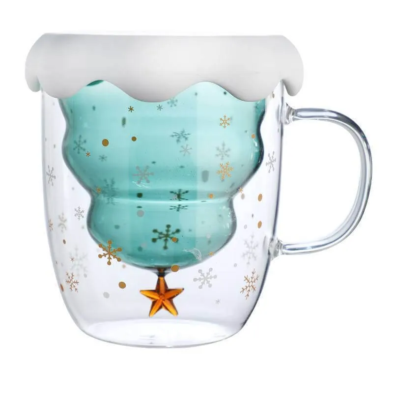 Glass mug with a snowflake design and an inverted Christmas tree inside. The tree is teal, topped with a white snow cap, and adorned with a gold star at the bottom.