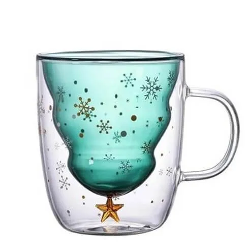 Clear glass mug with a teal, tree-shaped inner chamber decorated with gold and white snowflakes, featuring a small gold star on the bottom.