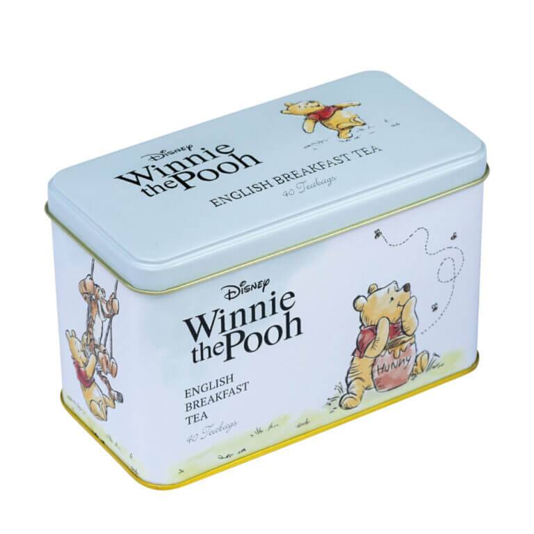 A charming tin featuring Winnie the Pooh illustrations, showcasing him savoring honey and swinging, adorned with "Winnie The Pooh - 40 Teabag Tin - English Breakfast" text.